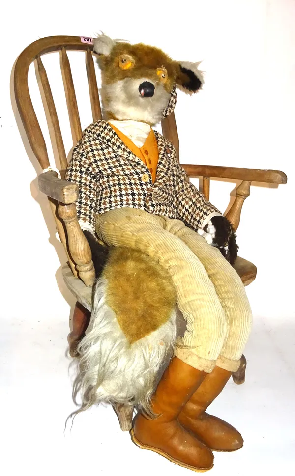 A 20th century toy fox wearing country clothing, seated on a child's ash and elm bow back armchair.  G6