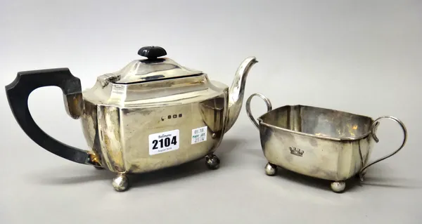 A silver teapot, of rectangular form, with curved corners, raised on four spherical feet, having composition fittings and a matching silver twin handl