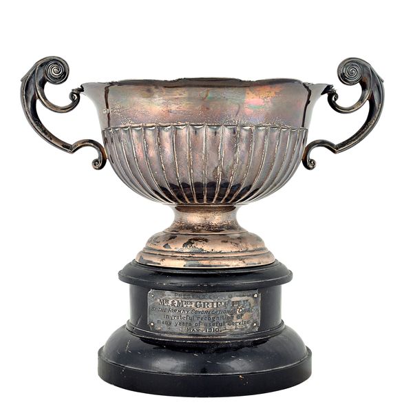 A silver twin handled trophy bowl, having a shaped rim, partly fluted decoration to the body and with scrolling handles, raised on a circular foot, Sh