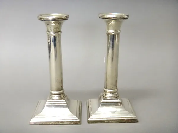 A pair of silver table candlesticks, each column raised on a square base (loaded), modern, height 17cm.