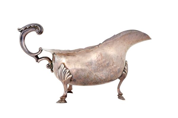 A silver sauceboat, having a shaped rim, scrolling handle and raised on three hoof shaped feet, in the 18th century taste, London 1905, weight 304 gms