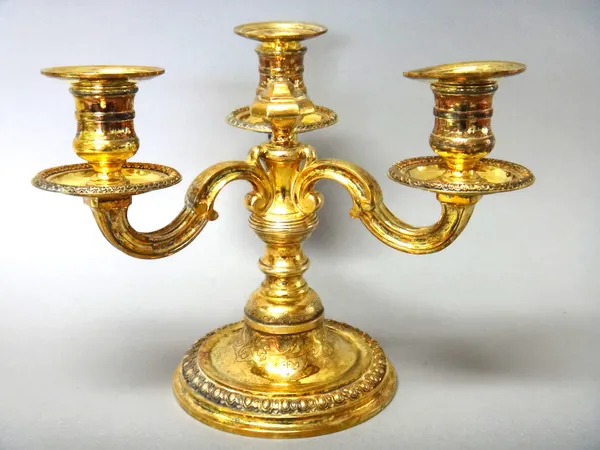 A French silver gilt three light table candelabrum, the three scrolled arms supporting individual candle holders of equal height, having detachable sc