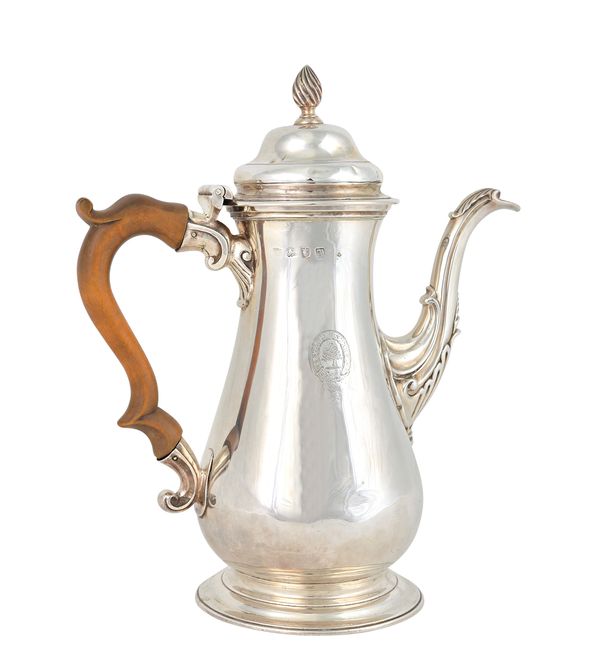 An early George III silver coffee pot, of baluster form, the hinged lid with a wrythen knop finial, the body crest engraved and raised on a circular f