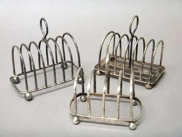 A silver seven bar toastrack, of arched form, with a looped shaped handle, raised on four spherical feet, Sheffield 1921, another silver seven bar toa