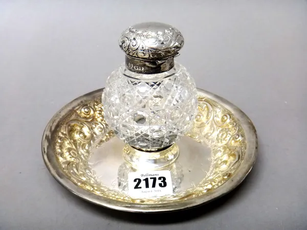 A Victorian silver circular inkstand, with floral and foliate embossed decoration, London 1891, fitted with a silver mounted spherical faceted glass,