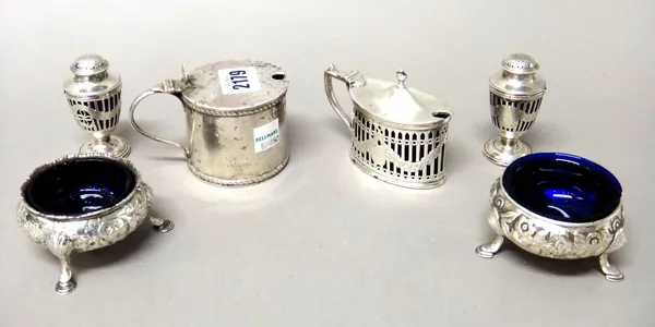 Silver condiments, comprising; a cylindrical mustard pot, probably Chester 1908, an oval mustard pot, with pierced and engraved decoration, Chester 19