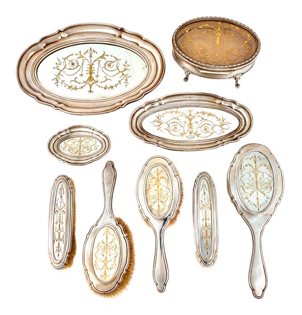 A silver and mirrored glass mounted nine piece lady's dressing set, comprising; an oval hinge lidded jewellery box, raised on four feet, three shaped