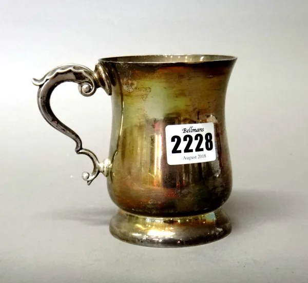 A silver christening mug of baluster form having a scrolling handle raised on a circular foot, Birmingham 1961, weight 220 gms.