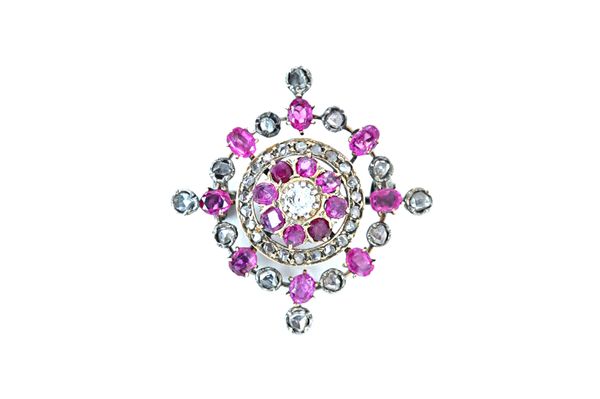 A diamond and ruby brooch, claw set with the principal cushion shaped diamond at the centre, in a surround of eight variously cut rubies, otherwise fu