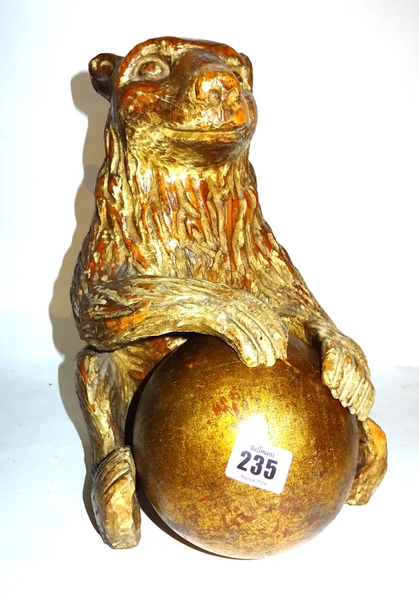 A large 20th century gilt painted wooden model of a bear, in the Black Forest style, holding a gilt ball, 34cm high.  F4