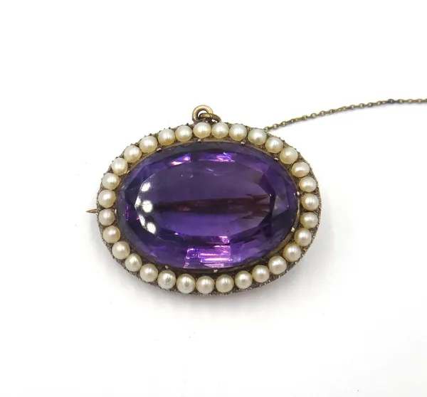 An amethyst and half pearl set oval brooch, the large oval cut amethyst mounted within a surround of half pearls, fitted with a safety chain.