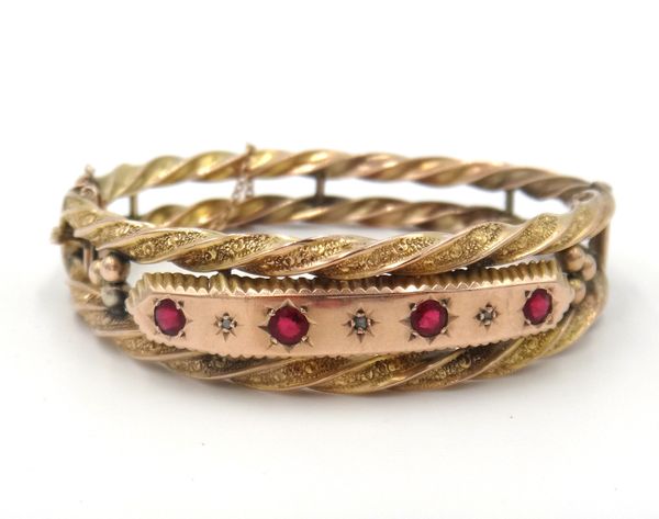 A 9ct gold, diamond and red gem set oval hinged bangle, the front mounted with four circular cut synthetic red gems and with three small diamonds at i