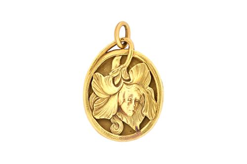 A French gold oval Art Nouveau pendant locket, the front decorated with the portrait of a girl within a pierced foliate spray, circa 1900, the back cr