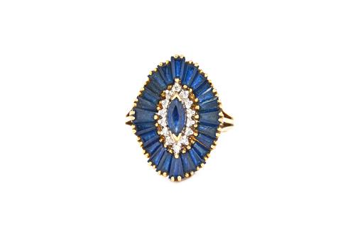 An 18ct gold, sapphire and diamond cluster ring, mounted with a marquise shaped sapphire to the centre, in a surround of circular cut diamonds and wit