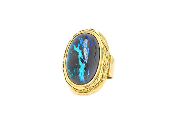 A gold and wood opal single stone ring, mounted with an oval cabochon wood opal, within a beaded raised surround, detailed 750, ring size R, with a ca