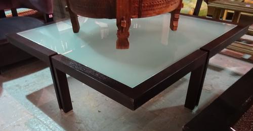 A modern hardwood square coffee table with glass top on four chrome capped supports, 125cm wide x 41cm high.   J8