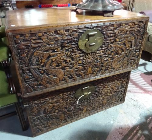 A pair of early 20th century carved Chinese camphor wood trunks on later plinth bases, 96cm wide x 45cm high, (2).  BAY 2