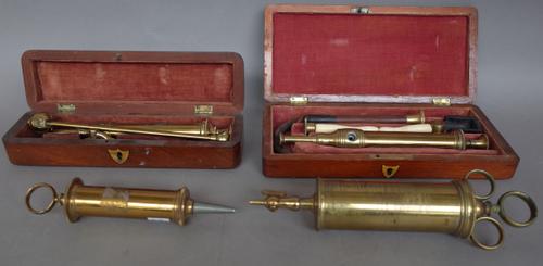 S. MAN London, an antique brass enema instrument comprising; two syringes and accessories, both in fitted mahogany cases and two further larger medica