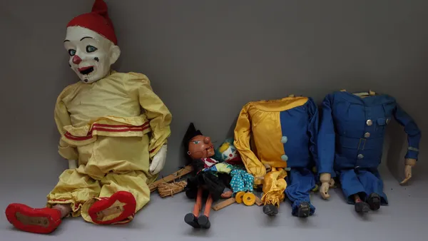 An early 20th century papier mache 'clown' puppet with moving eyes (sprung arms and wooden feet in a yellow suit, 65cm high, two further puppets; clow
