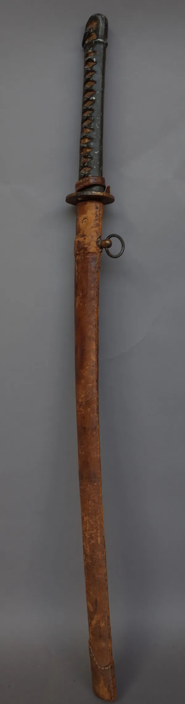 A Japanese Katana with polished steel blade, 62.5cm, iron tsuba and painted metal handle in a leather bound wooden scabbard.