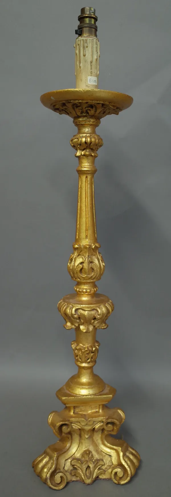 Two 17th century style giltwood altar candlesticks of fleur de lys scroll form, 20cm high and a giltwood table lamp, (converted) of similar style, 64c