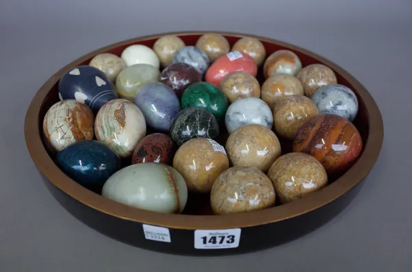 A quantity of hardstone eggs and spheres, late 20th century, arranged in a circular shallow lacquered dish, (30).