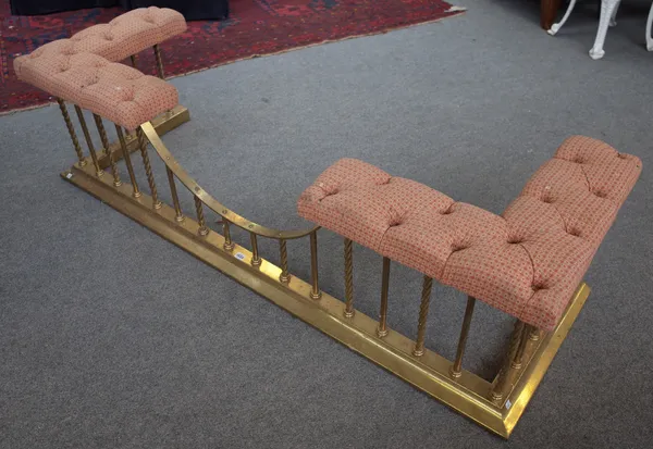 A Victorian style brass club fender on twisted supports with red ground button back upholstered corner seats, 175cm wide.