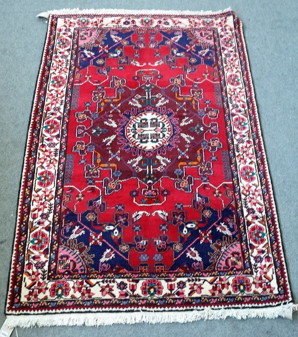 A Bakhtiari rug, Persian, the madder field with a bold dark madder medallion, indigo spandrels; an ivory rose and angular vine border, 204cm x 133cm.