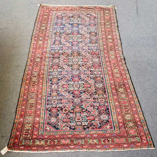 A Fereghan Kelleh carpet, Persian, the dark indigo filed with an allover herate design, minor spandrels, a sage flowerhead and vine border, 296cm x 15