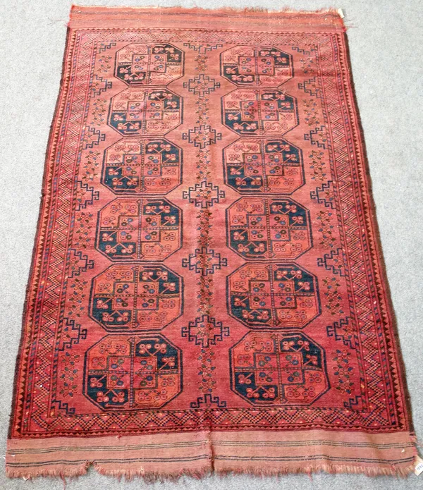 An Uzbek carpet, the madder field with two columns of six bold guls, supporting single hooked crosses; a zig-zag border, 250cm x 155cm.