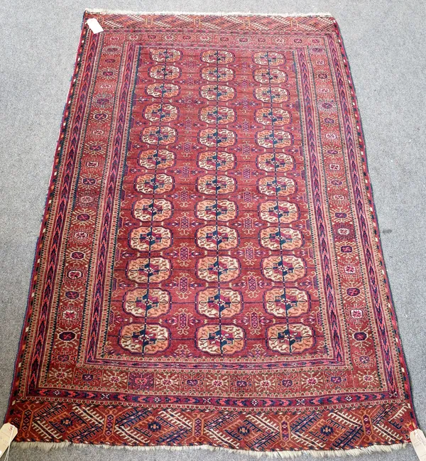 A Tekke Turkman rug, the madder field with three columns of twelve guls, supporting motifs, a madder sunburst border, 224cm x 139cm.