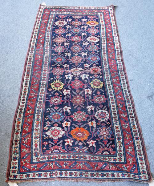 A Karabagh runner, Caucasian, the dark indigo field with rows of bold rosette flowerheads, angular vines and minor flowerheads, a madder leaf and star