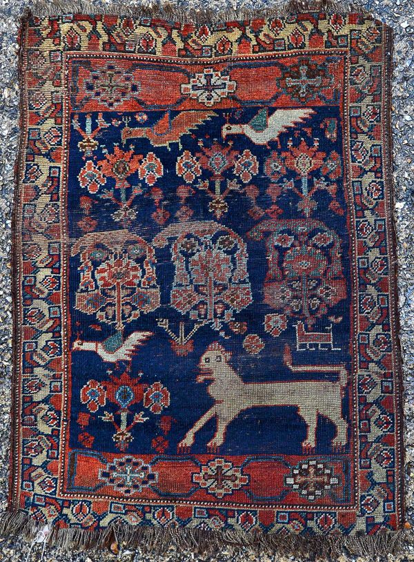 An Afshar mat, Persian, the dark indigo field with three bold botehs, a lion and four birds, an ivory flower pattern border, 95cm x 70cm. Illustrated.
