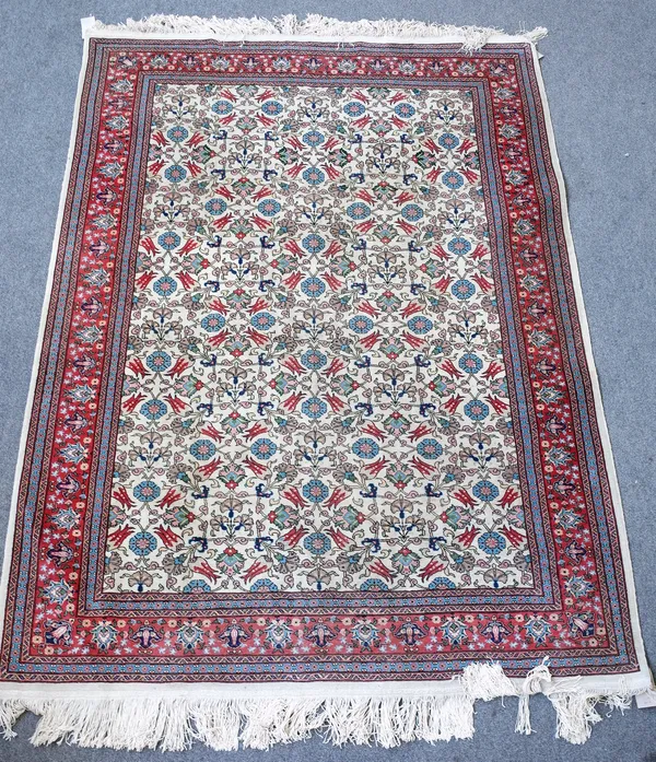 A Tabriz rug, Persian, the ivory field with an allover pattern of tulips, rosettes and carnations, a madder palmette and vine border, 242cm x 170cm.