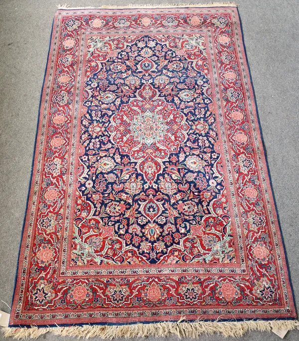 A Kashan rug, Persian, the indigo field with a madder medallion, matching spandrels, all with floral sprays, a madder rosette, spray and vine border,