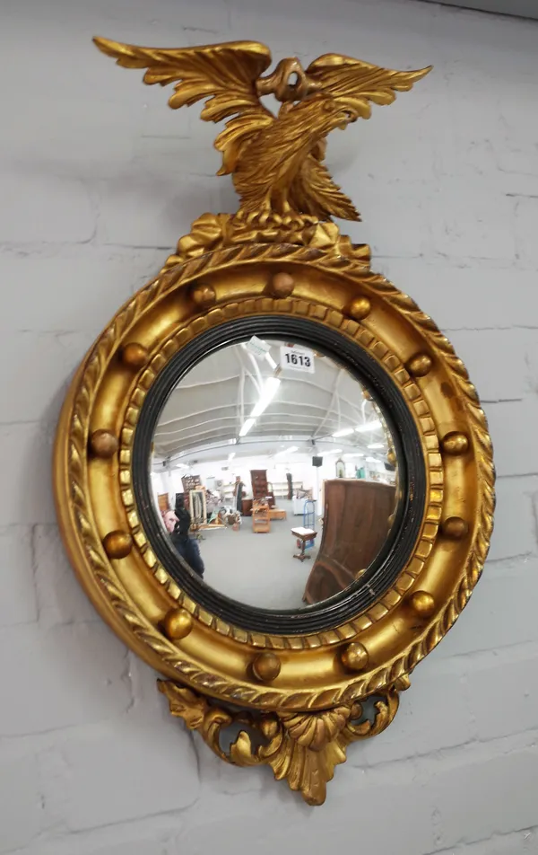 A small 19th century gilt framed convex wall mirror, with eagle finial, 38cm wide x 65cm high.