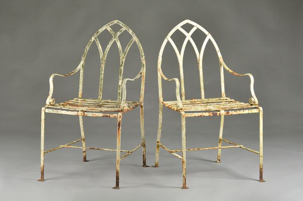 A pair of white painted Gothic Revival wrought iron garden chairs, in the Regency style, 54cm wide x 97cm high. Illustrated.