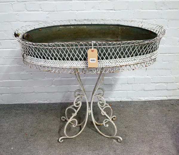 A 20th century white painted metal oval plant stand, on scroll base, 98cm wide x 90cm high.