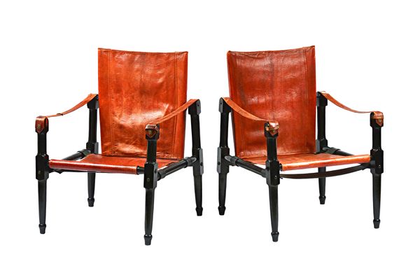 Roorkee, Safari; a pair of easy armchairs with rouge leather upholstery and strap work arms and turned ebonised frames, 62cm wide x 83cm high.
