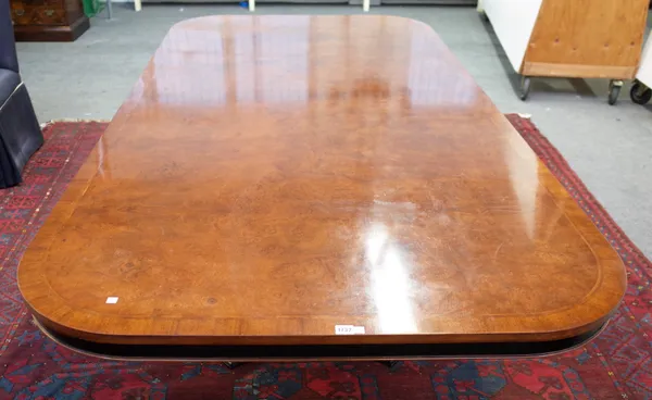 A Regency style figured walnut rounded rectangular dining table on flared octagonal column, 122cm wide x 240cm long.