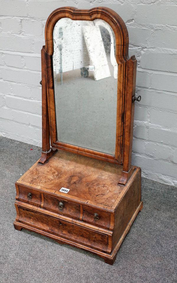 A Queen Anne figured walnut toilet mirror, the cushion base with three short and one long drawer, 42cm wide x 75cm high.