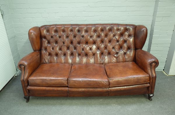 An early 20th century tan leather button upholstered wingback sofa, on squat cabriole supports, 188cm wide x 95cm high.