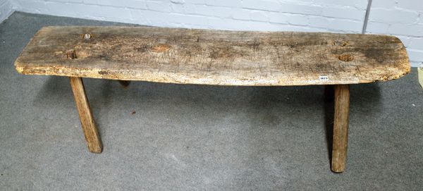 A 19th century rustic elm pig bench on four staked supports, 163cm wide x 48cm high.