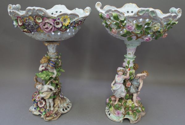 A Plaue porcelain figural comport, early 20th century, the pierced two handled basket supported on a foliate cast stem, surrounded by three young chil