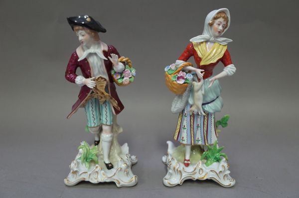 A pair of Sitzendorf porcelain figures, early 20th century, male and female, each modelled holding a basket of flowers and game, on a gilt scroll base