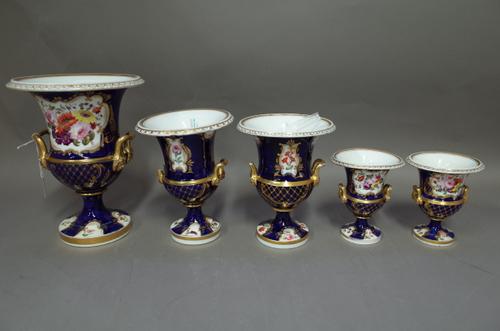 A Coalport porcelain five-piece garniture of vases, circa 1820, each of two-handled campana form, painted with panels of flowers inside gilt frames ag