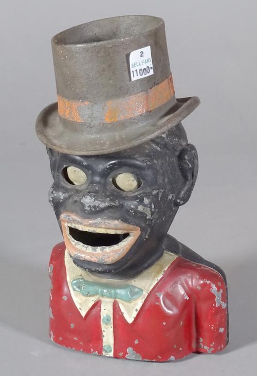 An early 20th century cast iron Golliwog money box, (lacking an arm), 20cm high, (a.f).   CAB