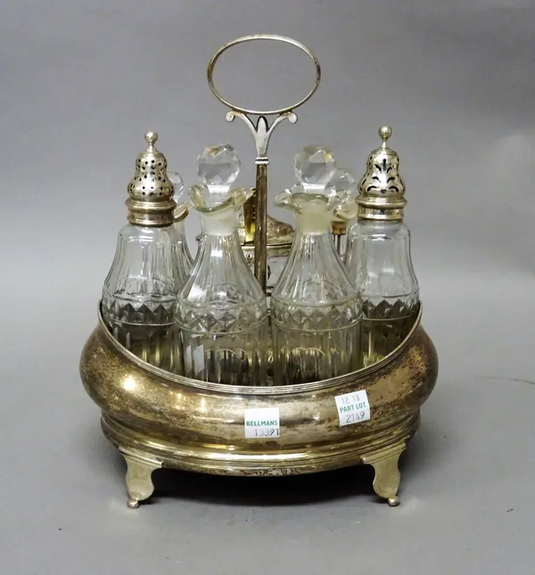 A George III silver cruet frame, the stand of oval form, with a loop shaped handle and raised on four feet, the base fitted with a mahogany panel, wit