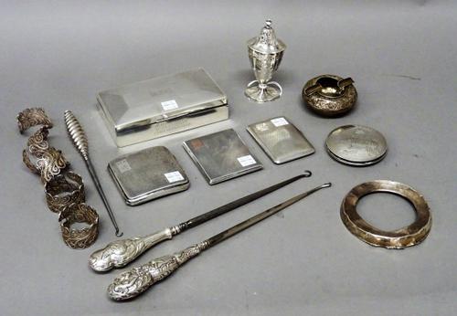 Silver and silver mounted wares, comprising; a rectangular table cigarette box, three cigarette cases, an urn shaped pepperette, with a blue glass lin