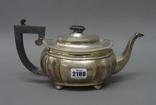 A silver teapot, of fluted bombe form, raised on four bun feet with black fittings, Chester 1923, gross weight 637 gms.